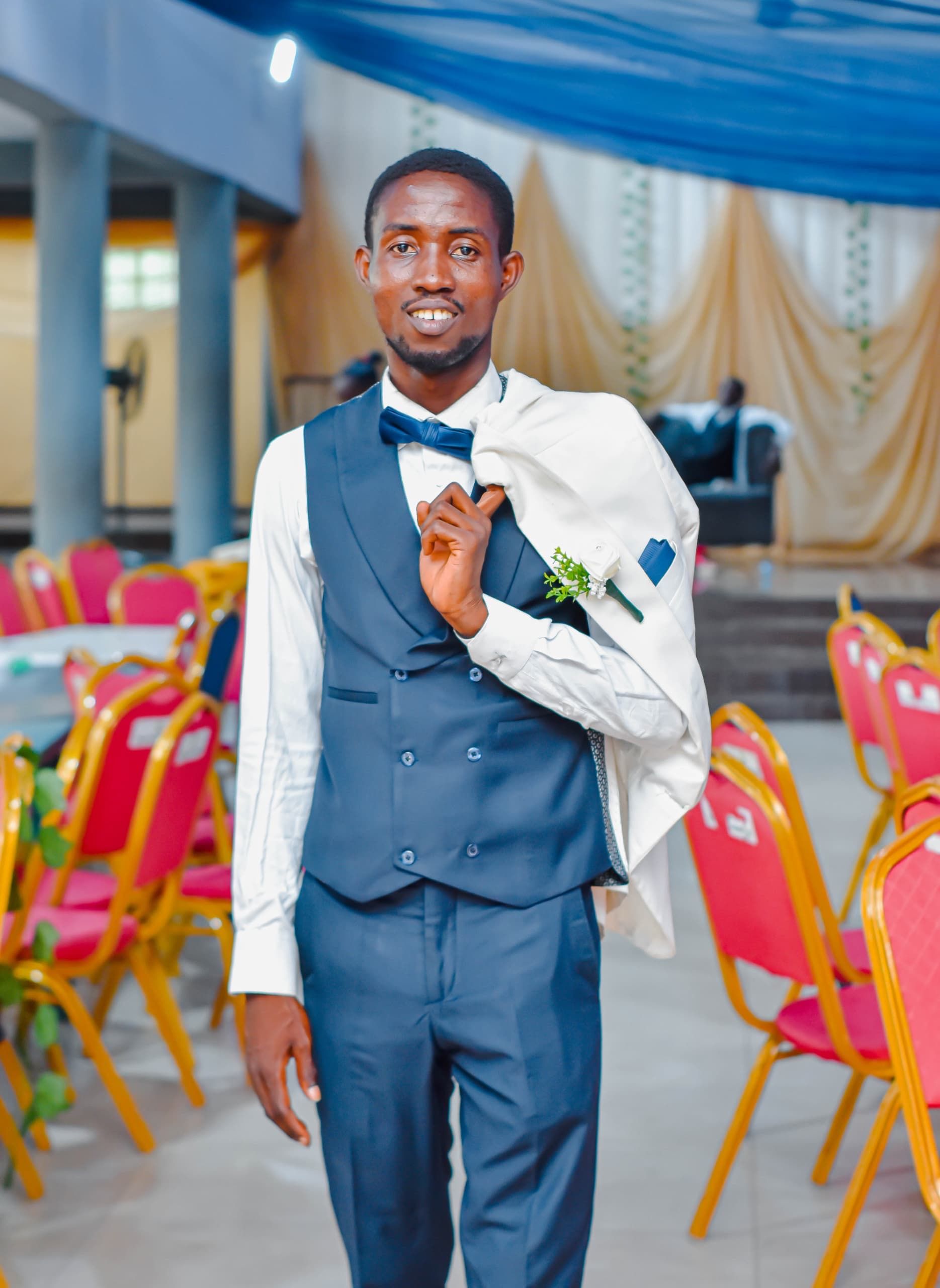 A stylish man in formal wedding attire posing confidently indoors.