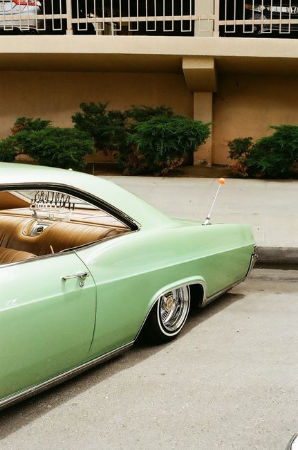 Retro green car parked curbside in an urban setting, showcasing vintage style.