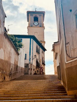 Picturesque stairway leading to a charming clock tower in Cehegín, Spain.