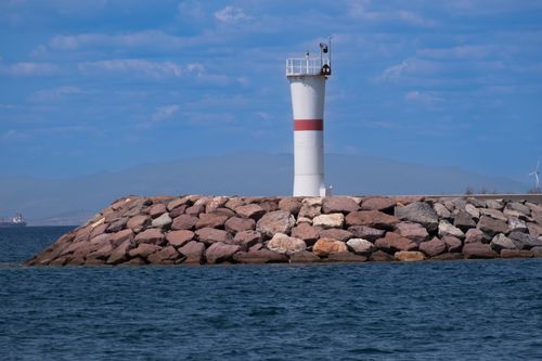 Free View of a lighthouse on a rocky coast in Foça, İzmir with blue skies and calm sea. Stock Photo