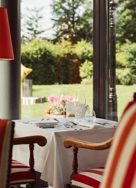 Luxury dining setup at a French restaurant overlooking a lush garden in Vonnas, France.