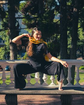 A woman performs a modern dance pose in a Buenos Aires park.