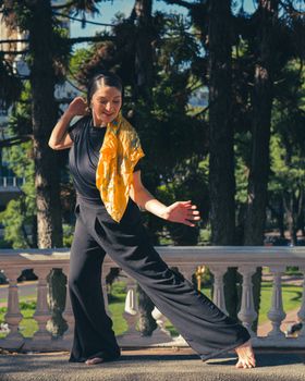 Woman gracefully dancing in an outdoor Buenos Aires park, vibrant scarf accentuating movement.