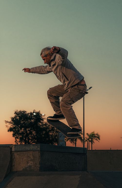 Free Senior adult enjoying skateboarding at a park during sunset, showcasing active lifestyle. Stock Photo
