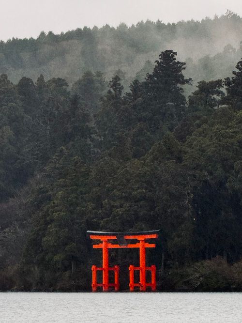 Free Captivating view of iconic Torii gate at lake's edge amid a misty forest setting in Japan. Stock Photo