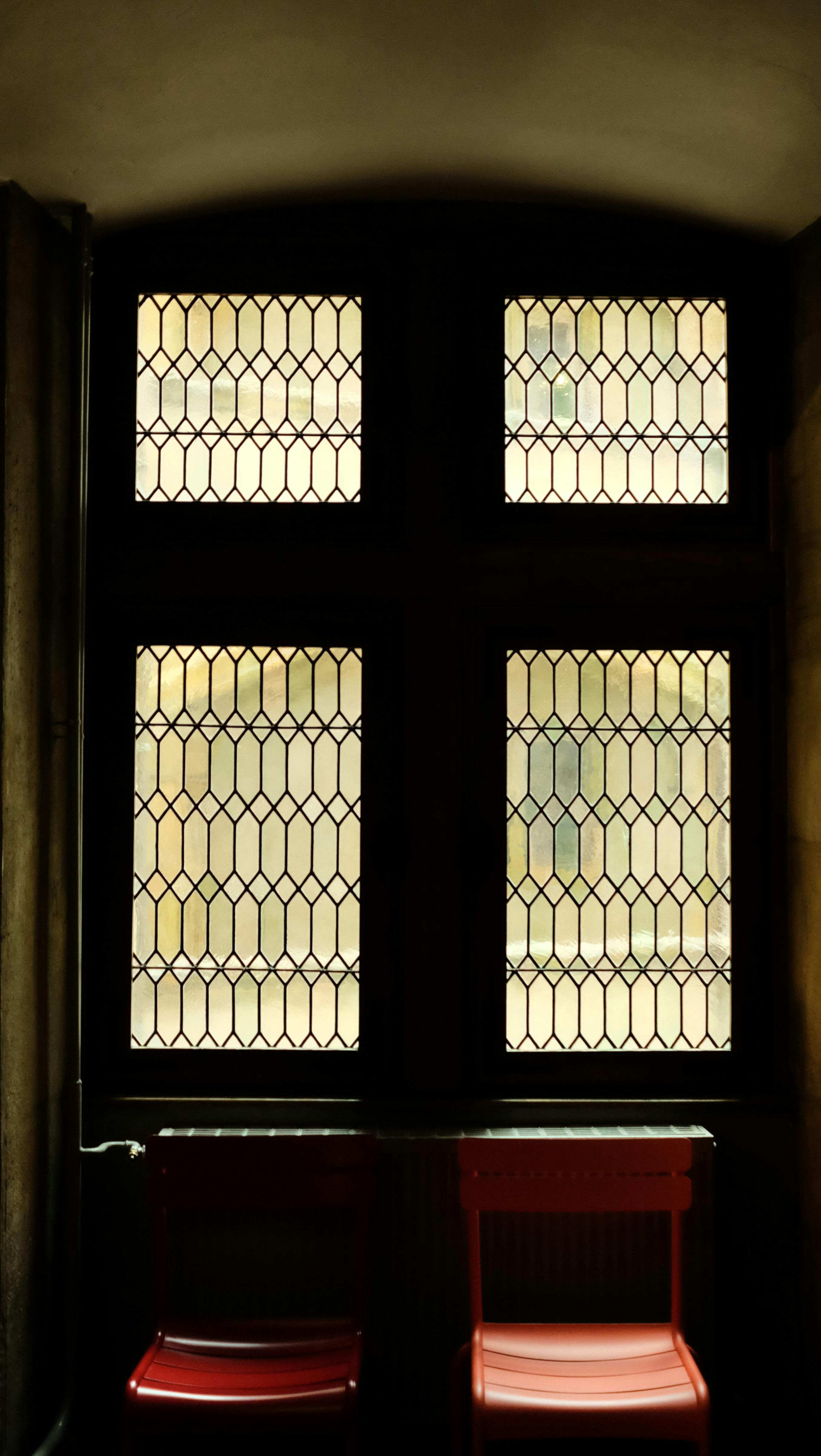 Kostenlos Stimmungsvolles Interieur mit Buntglasfenster und roten Stühlen in Lyon, Frankreich. Stock-Foto