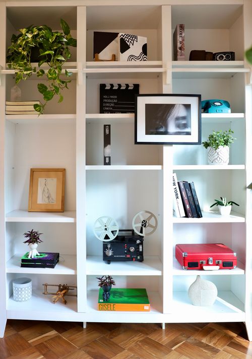 Free Contemporary bookshelf featuring vintage decor items, books, and greenery for a stylish home interior. Stock Photo