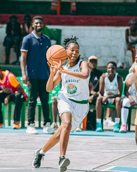 Energetic female basketball player dribbling during a game outdoors.