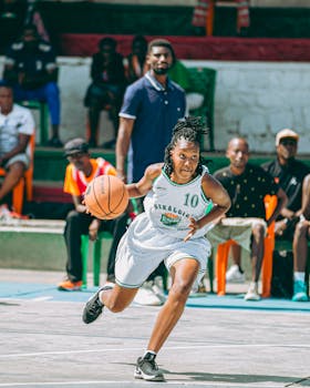 Female basketball player driving down the court during an outdoor game.