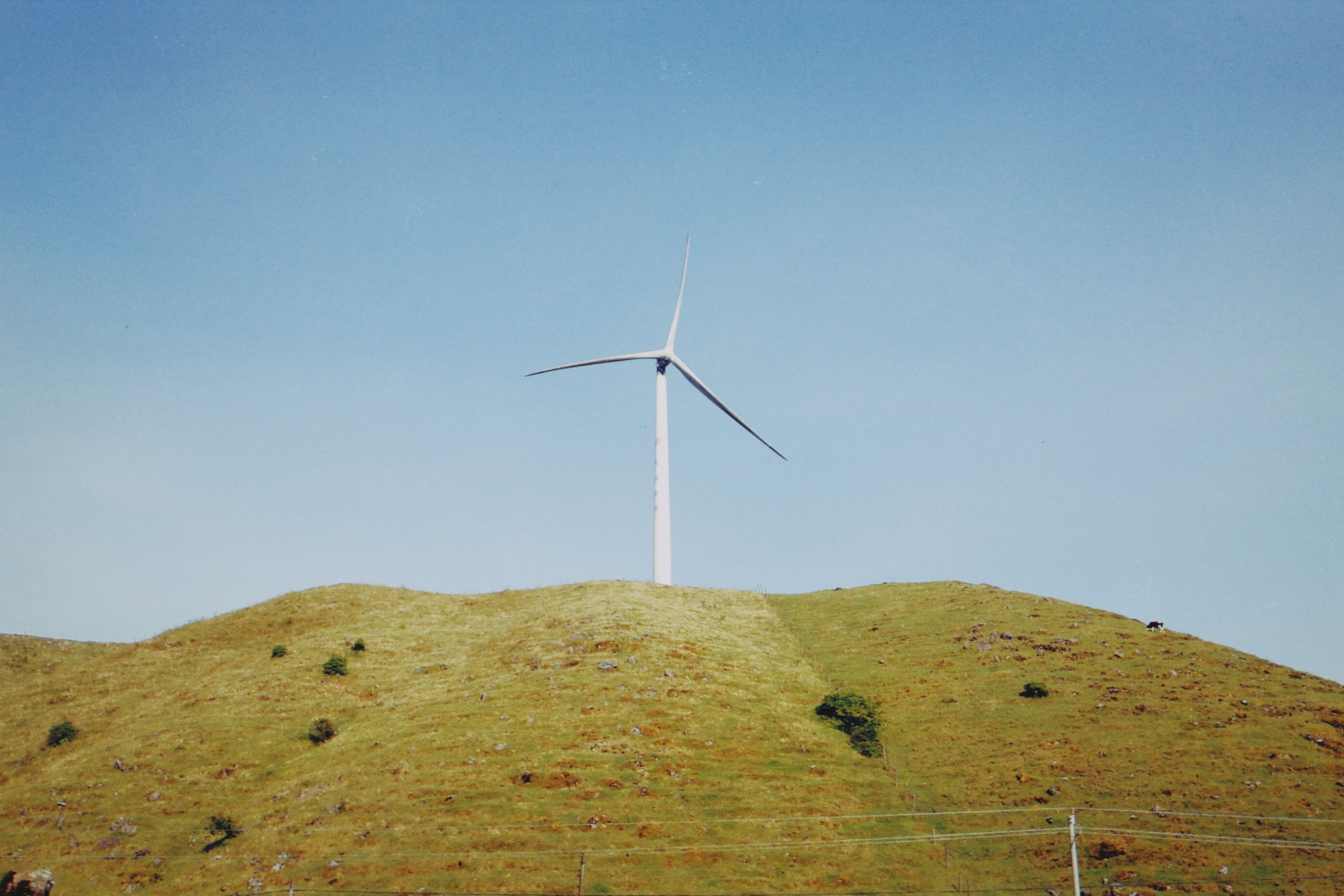 Wind Turbine on Grass Hill Under Clear Sky · Free Stock Photo