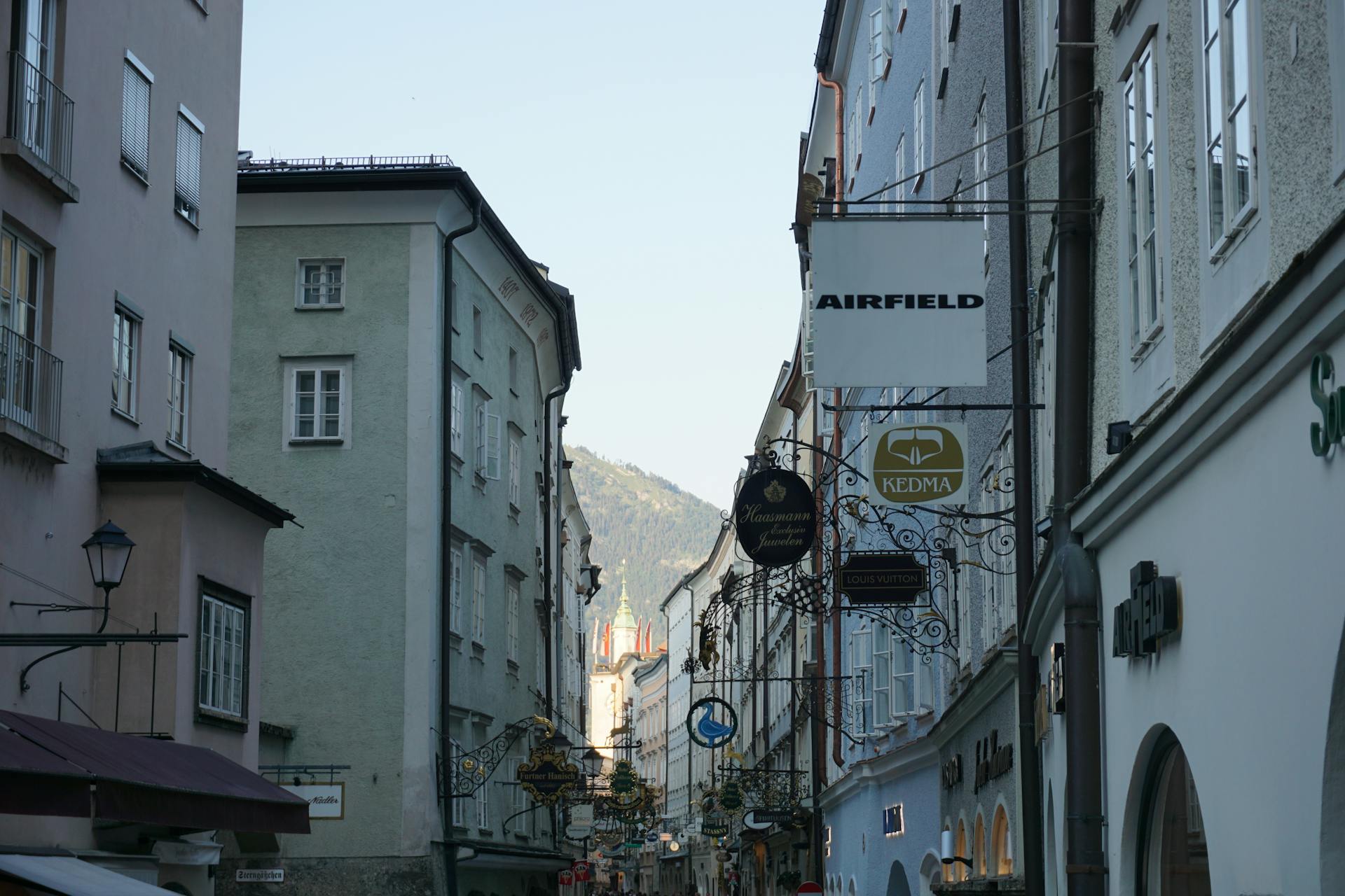 Picturesque view down a street in SalzburgAustria featuring historic architecture and distant mountains.