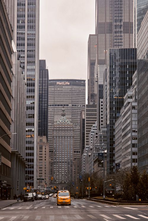 Free Yellow taxi driving on a busy street in Manhattan, New York with skyscrapers in the background. Stock Photo
