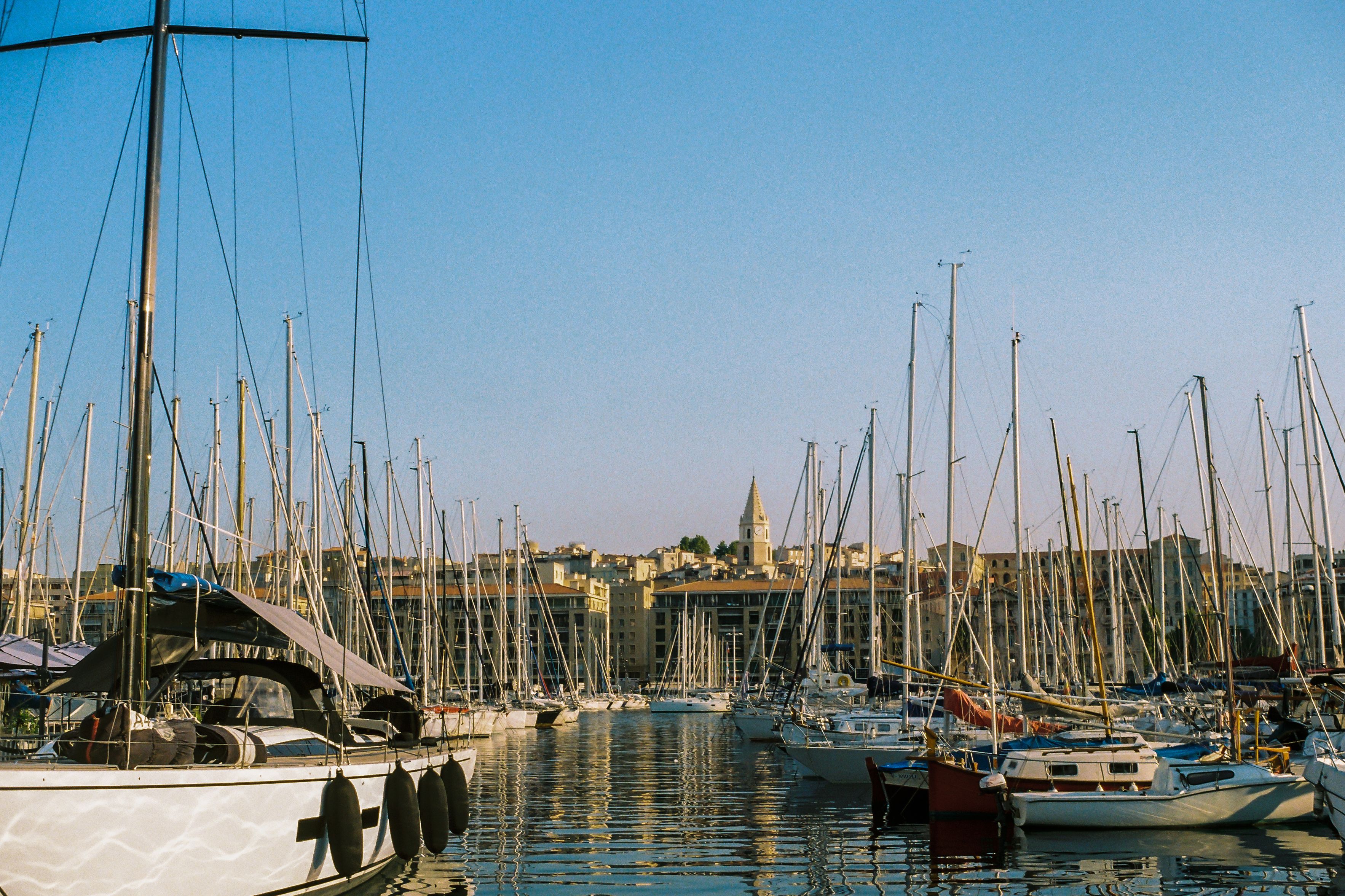 Explore the bustling Old Port in Marseille with sailboats under a bright sky.
