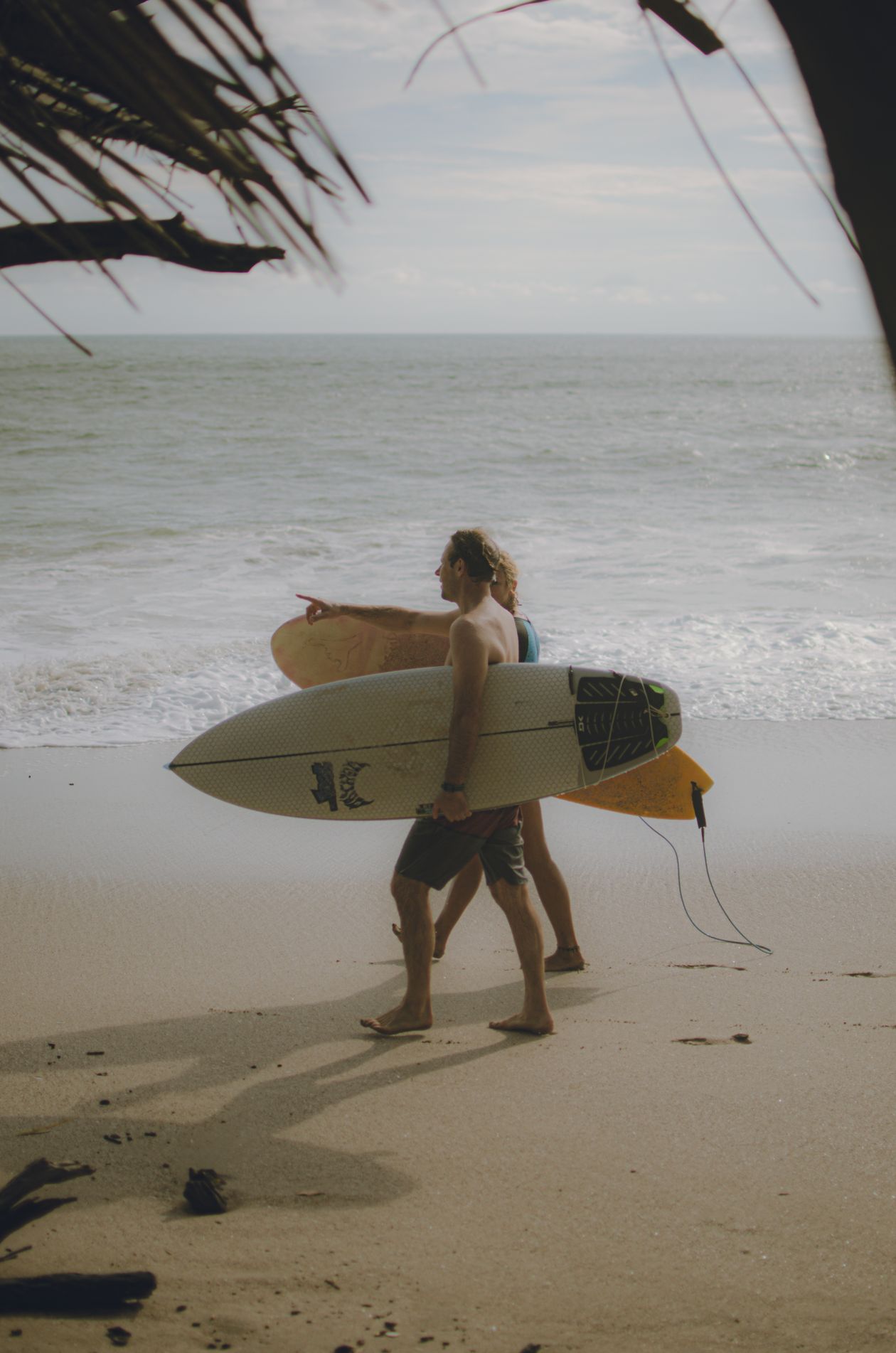 Hai người bạn vác ván lướt sóng dạo bước trên bãi biển Tamarindo, Costa Rica