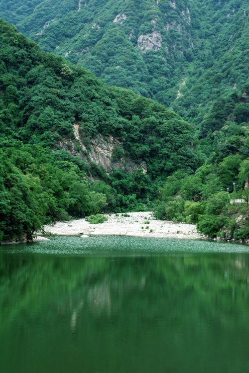 Free Serene mountain landscape with lush greenery and calm lake reflecting the hills. Stock Photo
