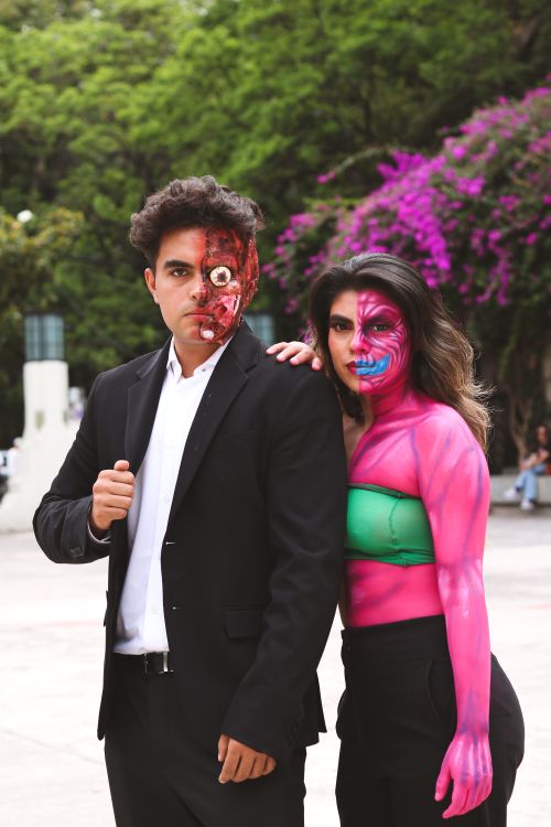 Free Man and woman in creative cosplay with face paint posing outdoors with vibrant greenery. Stock Photo