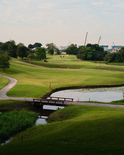 Free Lush green golf course landscape with a bridge crossing and serene pond view. Stock Photo
