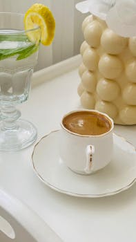 Minimalist coffee and lemon water setup with vase on a white tray. Perfect morning routine.