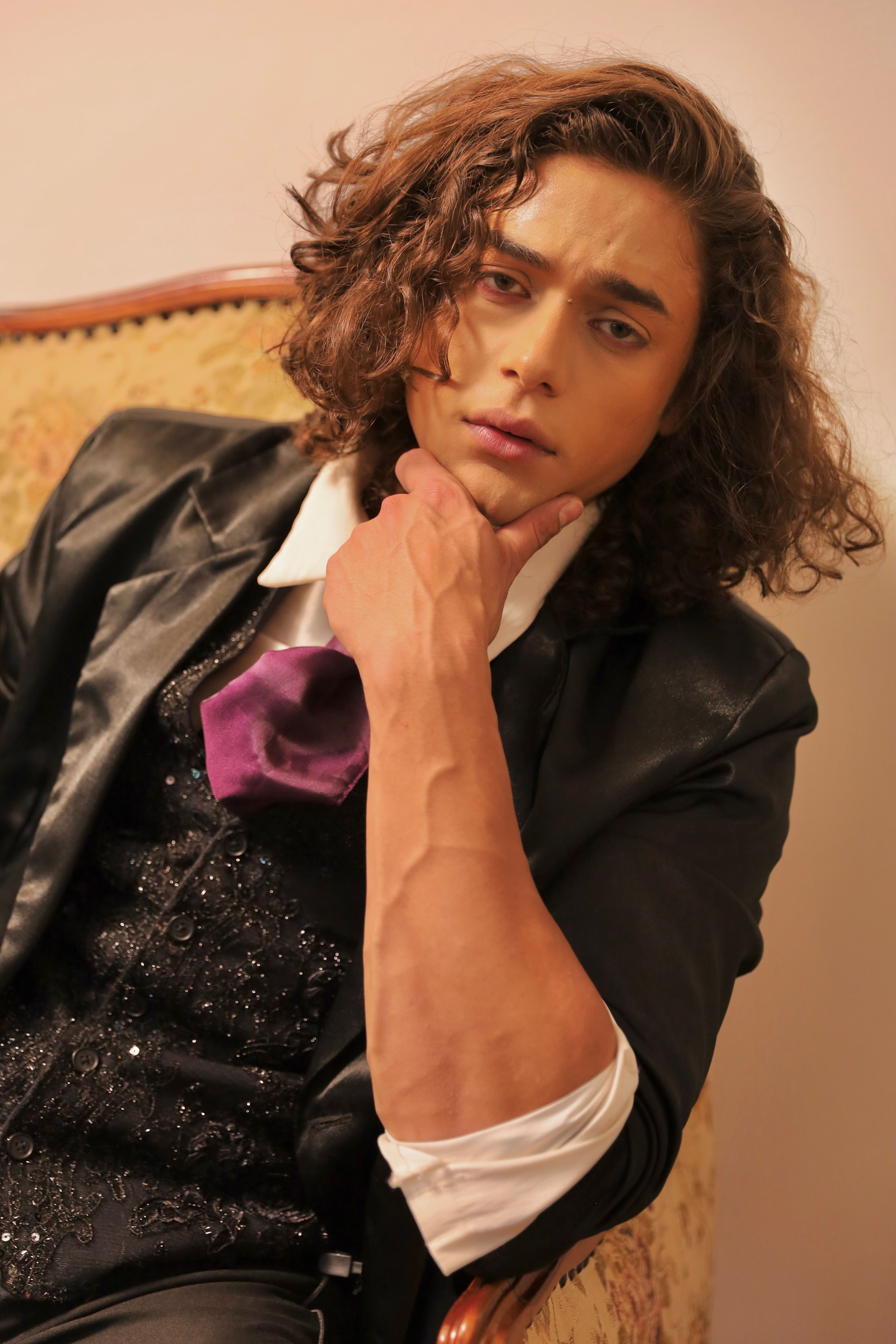 Portrait of a stylish young man with curly hair in formal attire, conveying modern fashion expression.