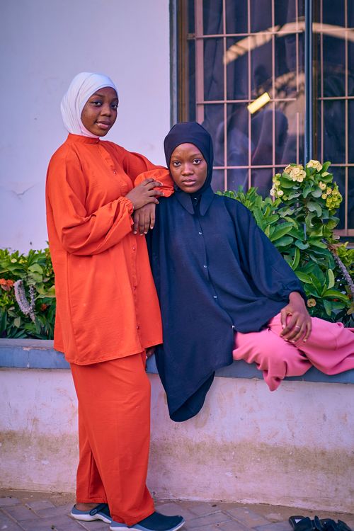 Free Two women in colorful hijabs posing confidently outdoors with flowers. Stock Photo