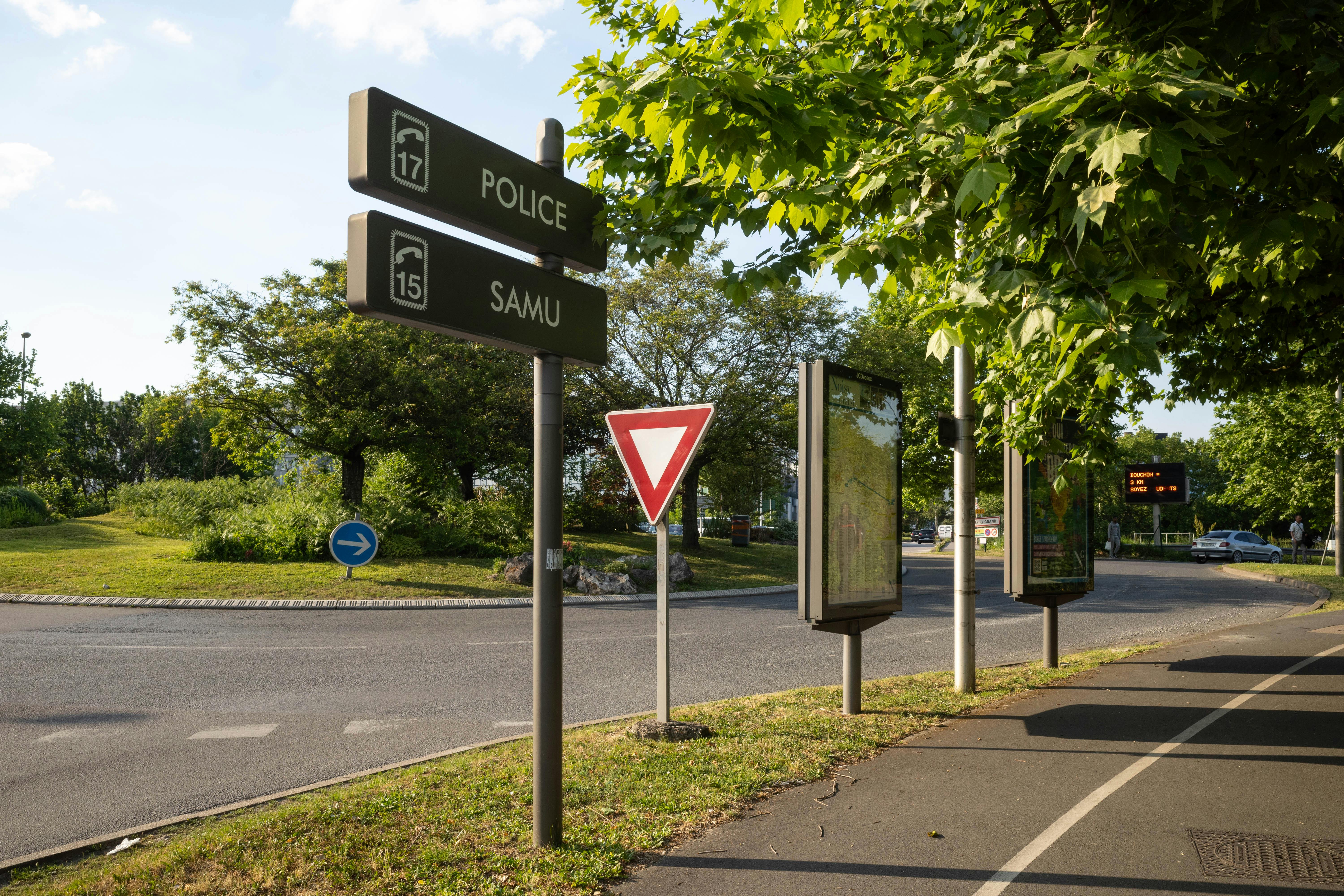 Roundabout in France with traffic signs and lush greenery on a sunny day.