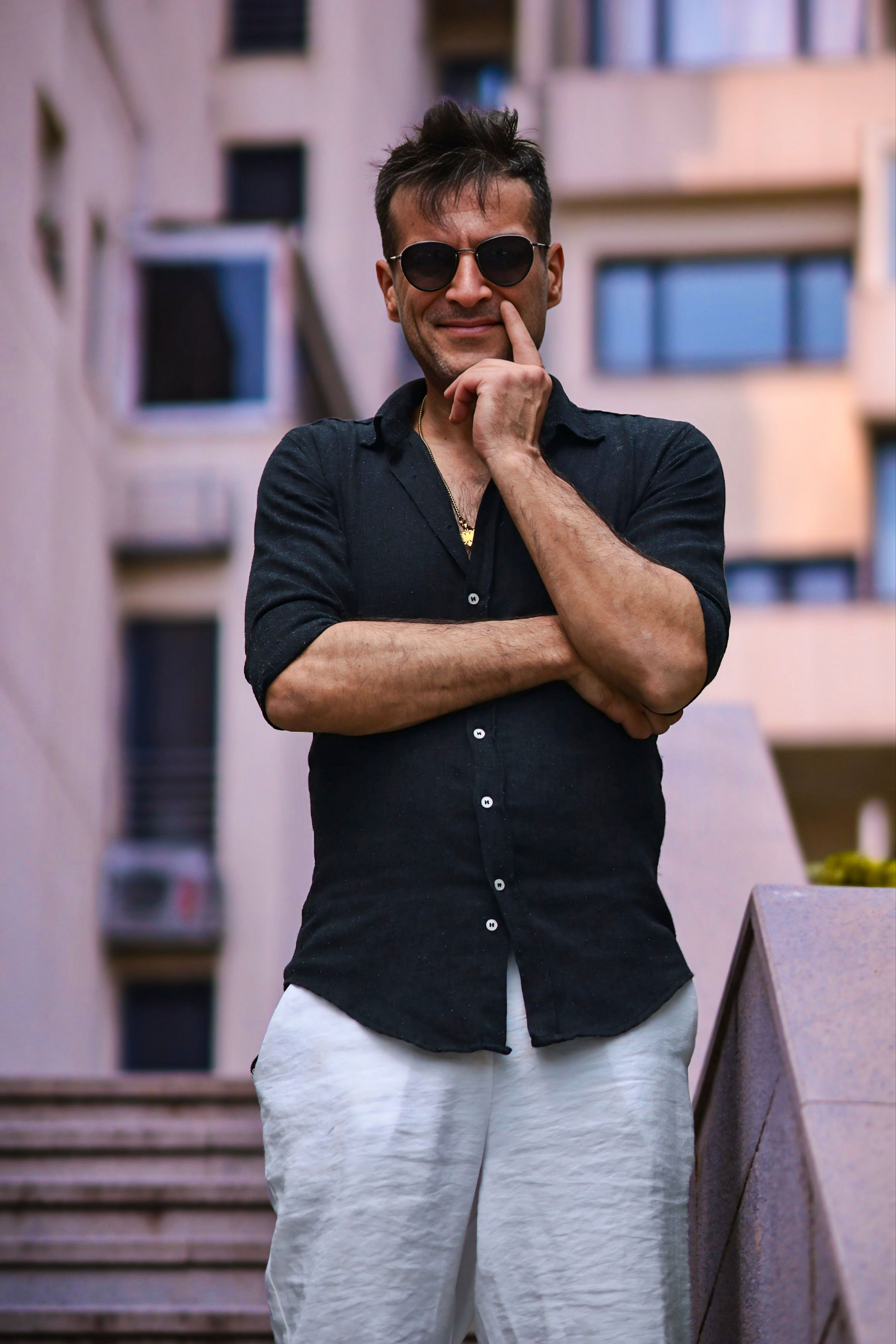 Stylish man in urban setting wearing sunglasses, exuding confidence.