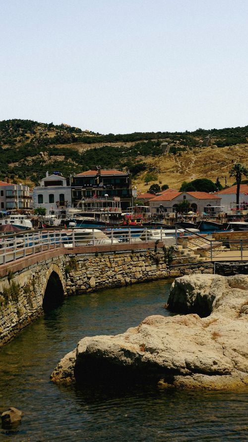 Free Picturesque view of a coastal village with stone bridge, reflecting historic architecture and serene nature. Stock Photo