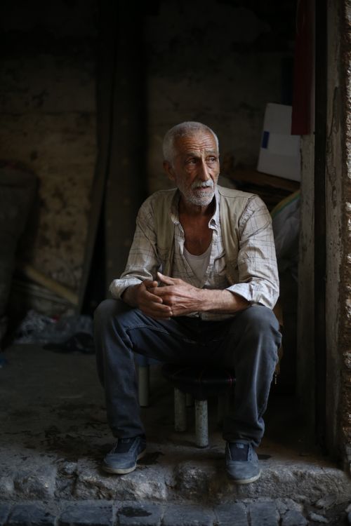 Free Elderly man sitting and contemplating in a dim, rustic environment. Stock Photo