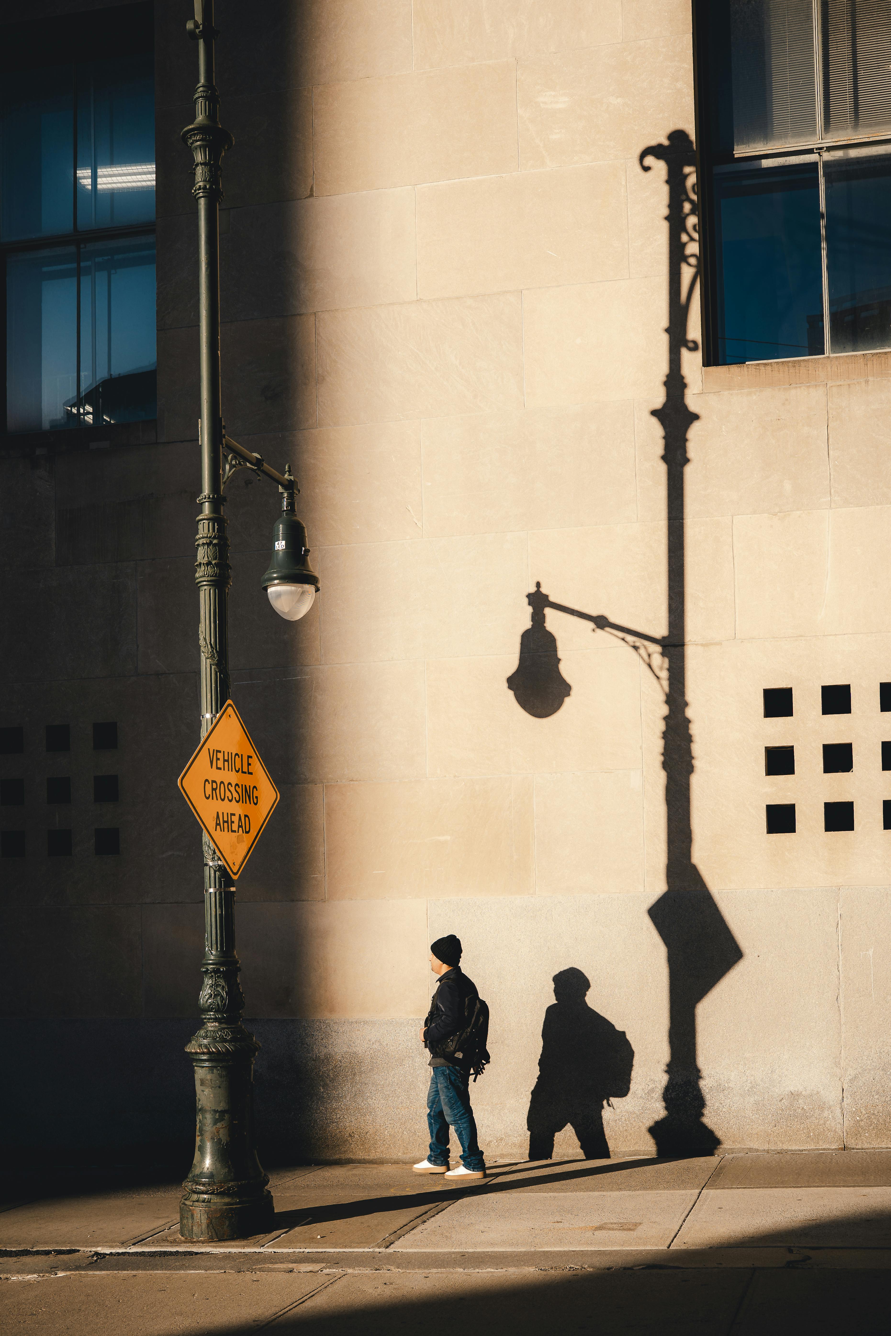 Free A person walks under dramatic shadows in a New York City street scene, featuring architectural details. Stock Photo