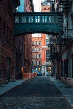 Quiet alleyway in NYC featuring urban architecture and a classic skybridge.