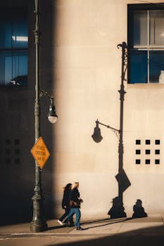 Silhouettes of two women walking along a wall in New York City, casting long shadows in the afternoon sun.
