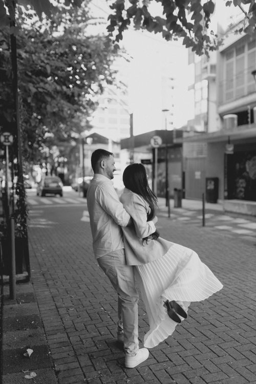 Free A black and white photo of a couple embracing joyfully on a city street. Stock Photo