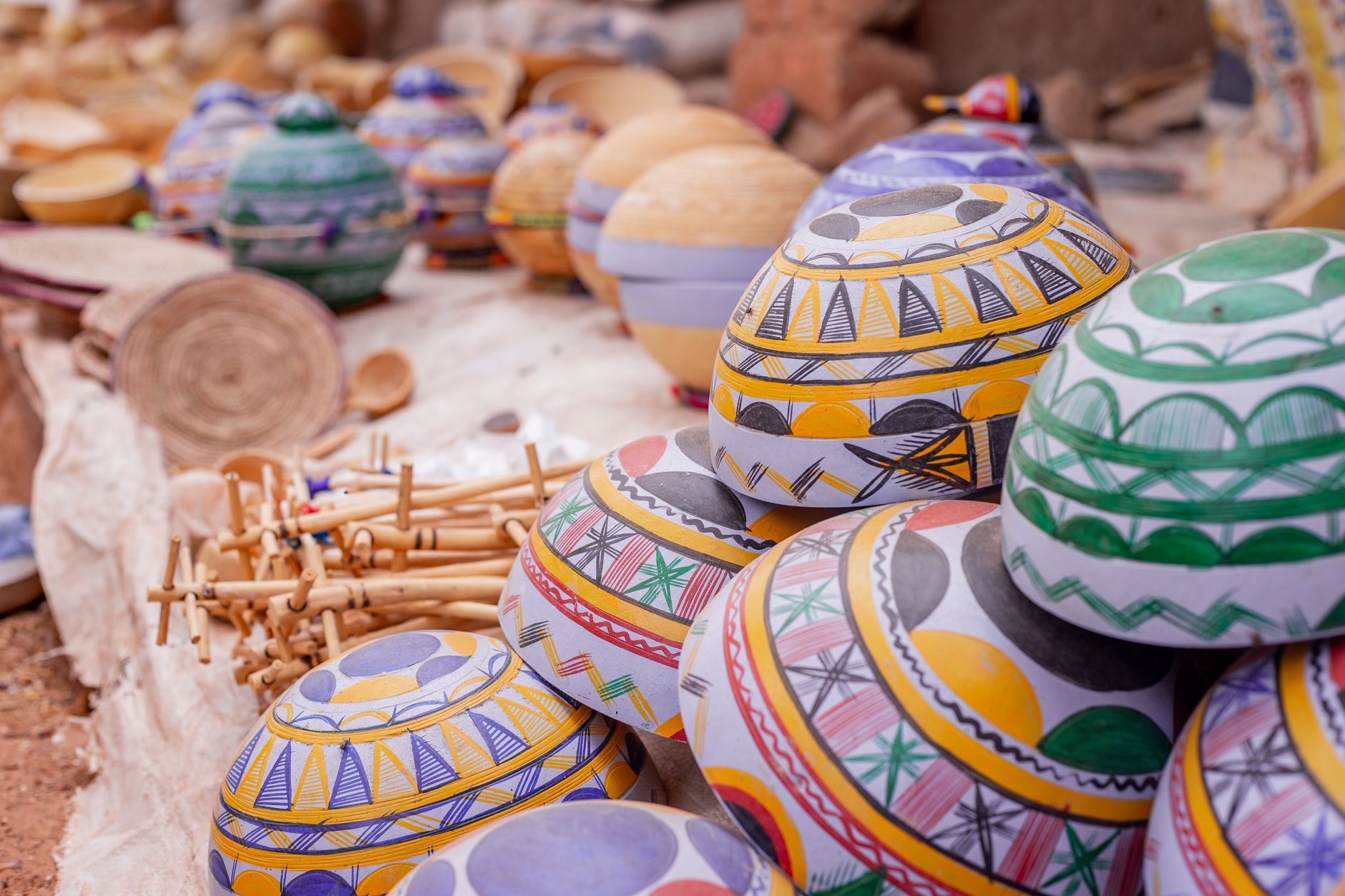 Vibrant African pottery with colorful patterns on display at an outdoor market.