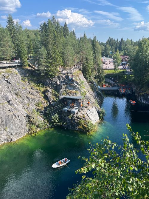 Free A picturesque lake surrounded by lush forest, cliffs, and a small boat. Stock Photo
