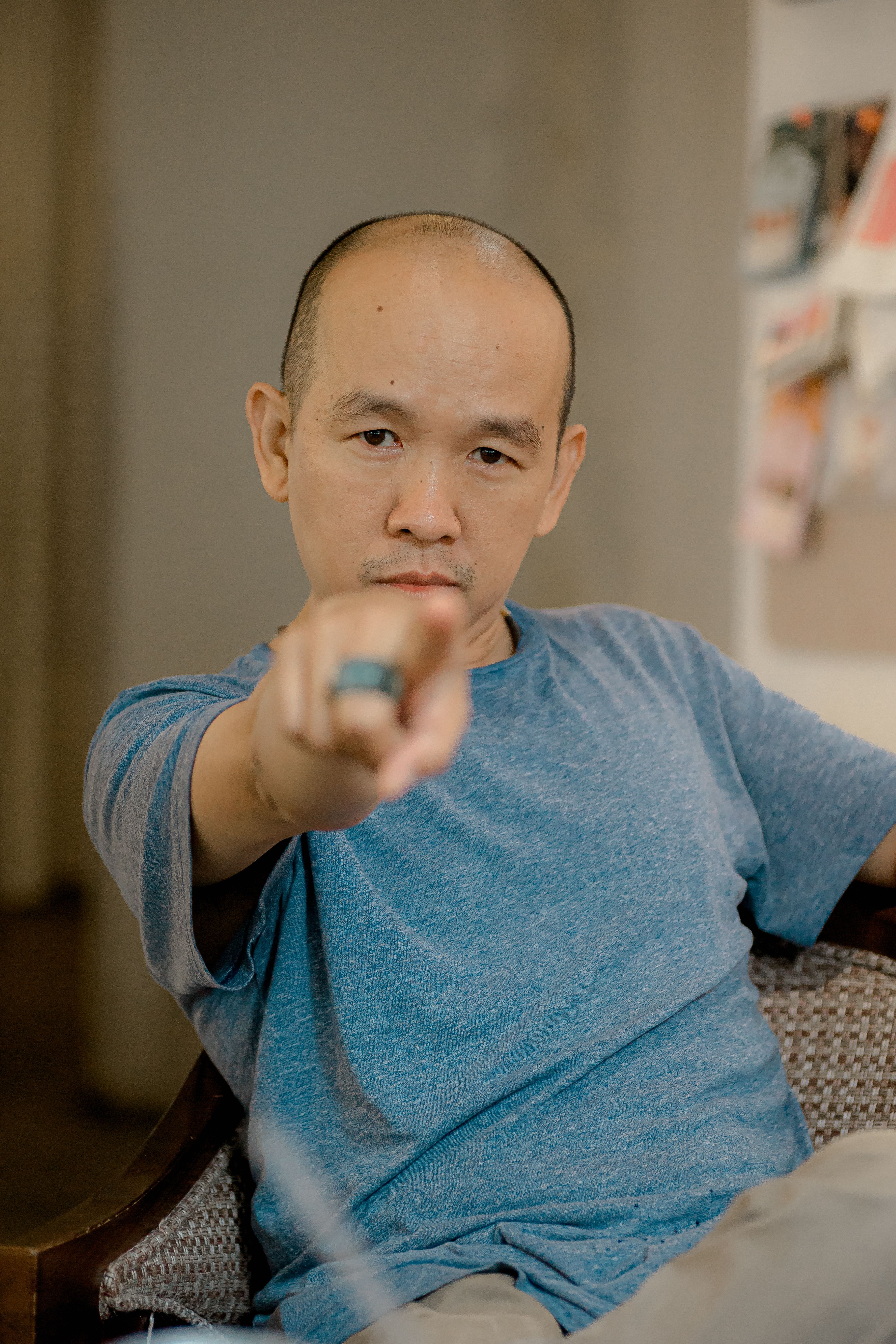 Serious man in casual attire pointing forward indoors, conveying intent.