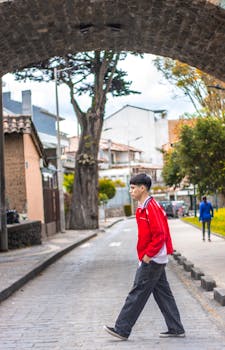 A young man walks under an arch in Cuenca, Ecuador, depicting a vibrant street scene.