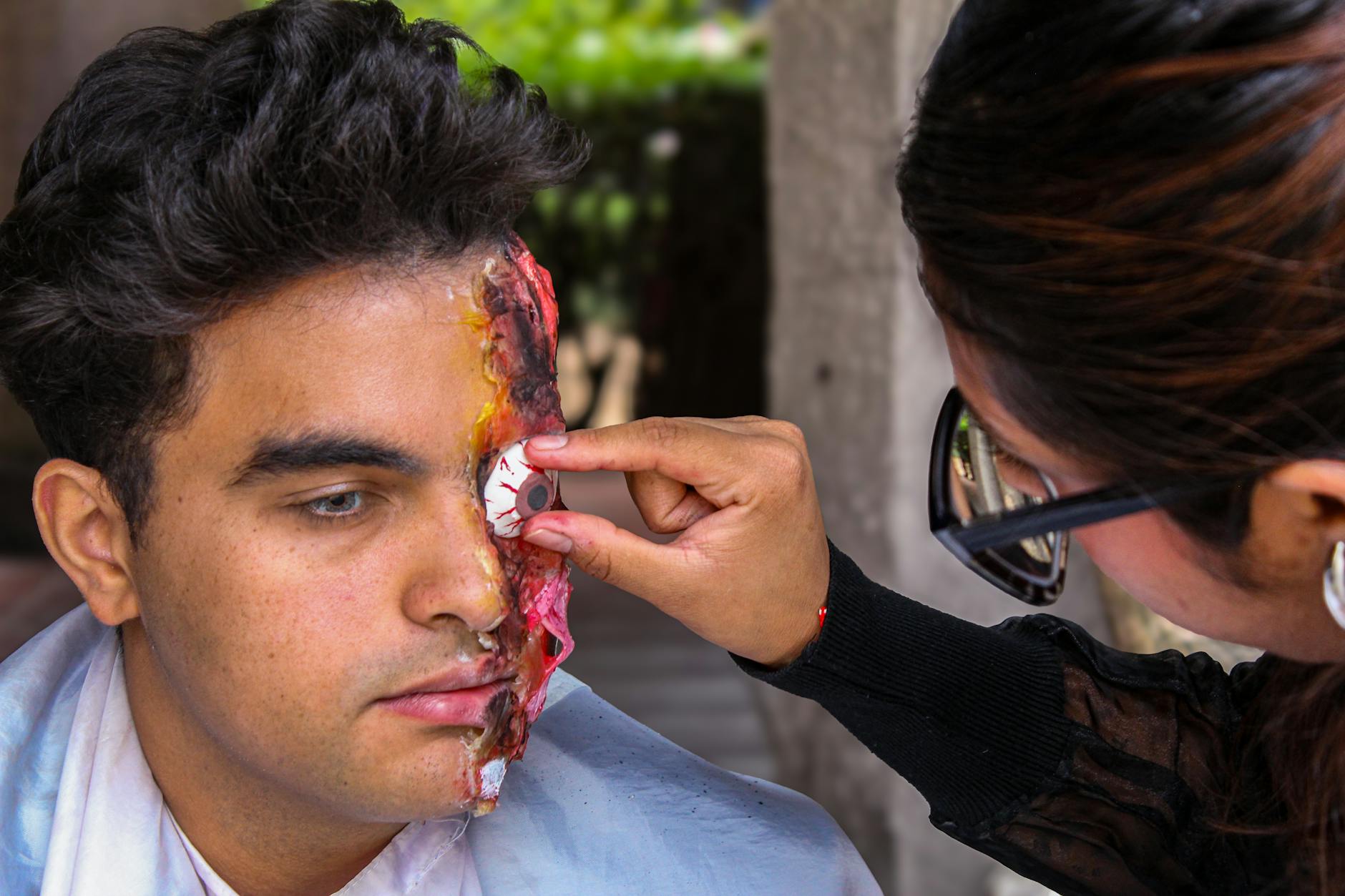 A close-up of special effects makeup being applied, showing the transformation process by a skilled artist.