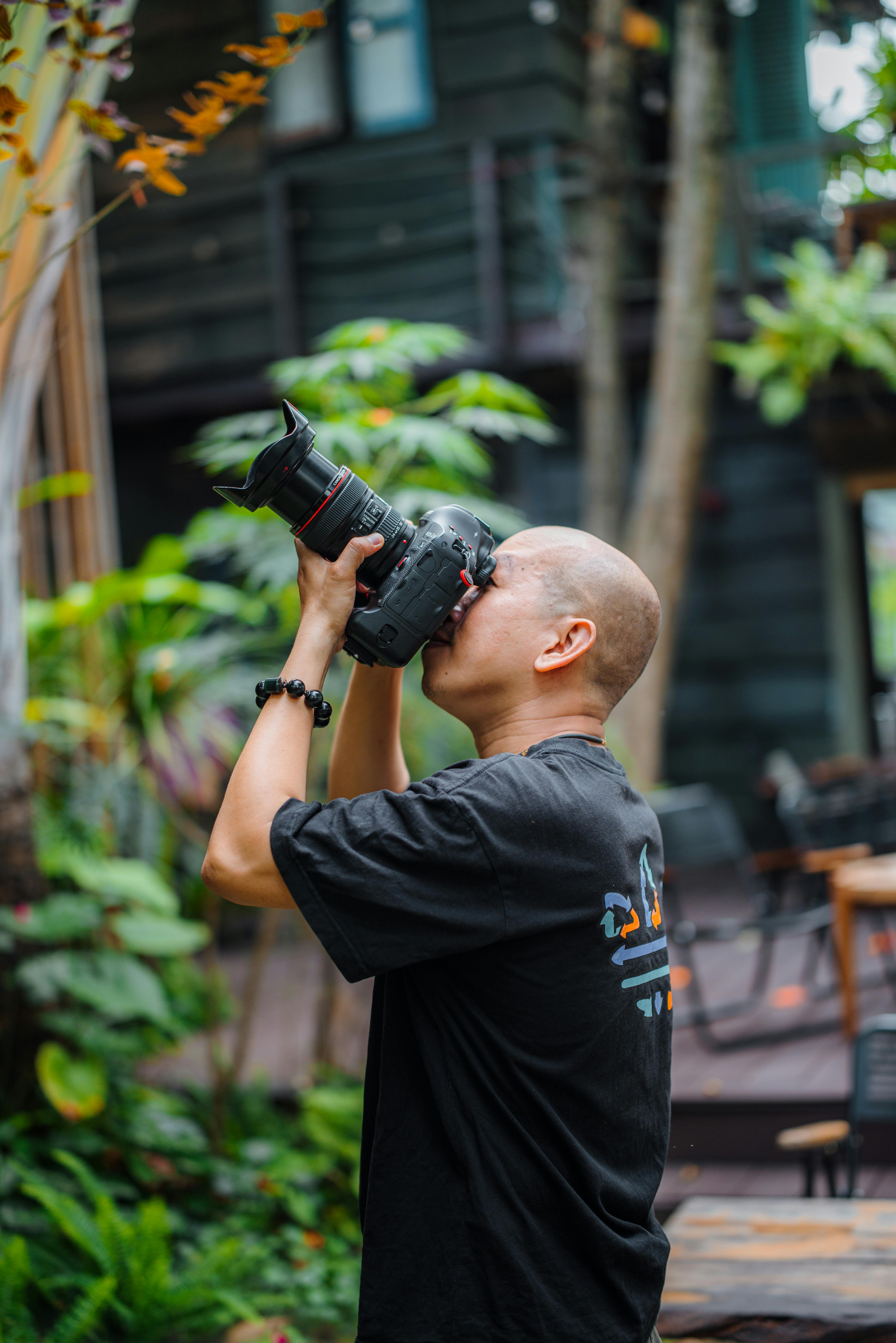 Free A photographer taking a photo outdoors, surrounded by lush greenery. Stock Photo