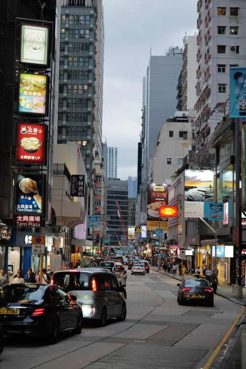 Free Vibrant city street with cars and pedestrians under evening lights, showcasing urban life. Stock Photo