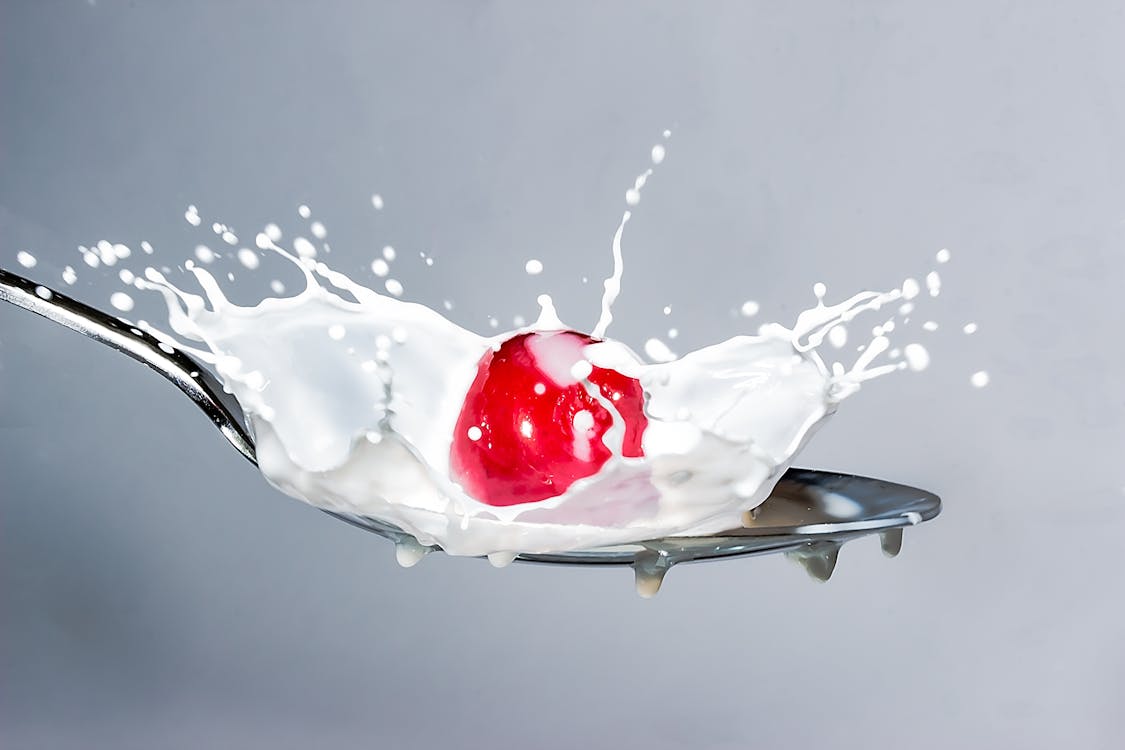 Free A high-speed capture of a milk splash featuring a cherry on a spoon, highlighting motion and liquid dynamics. Stock Photo