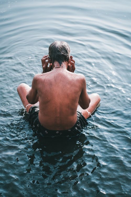 Free An elderly man engages in a peaceful ritual bath in the serene waters of Lucknow, India. Stock Photo