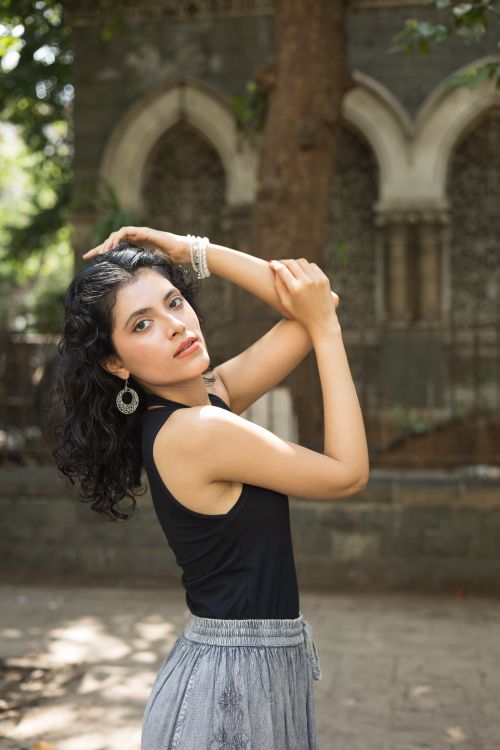 Free Stylish woman in black top posing gracefully outdoors against an architectural archway. Stock Photo