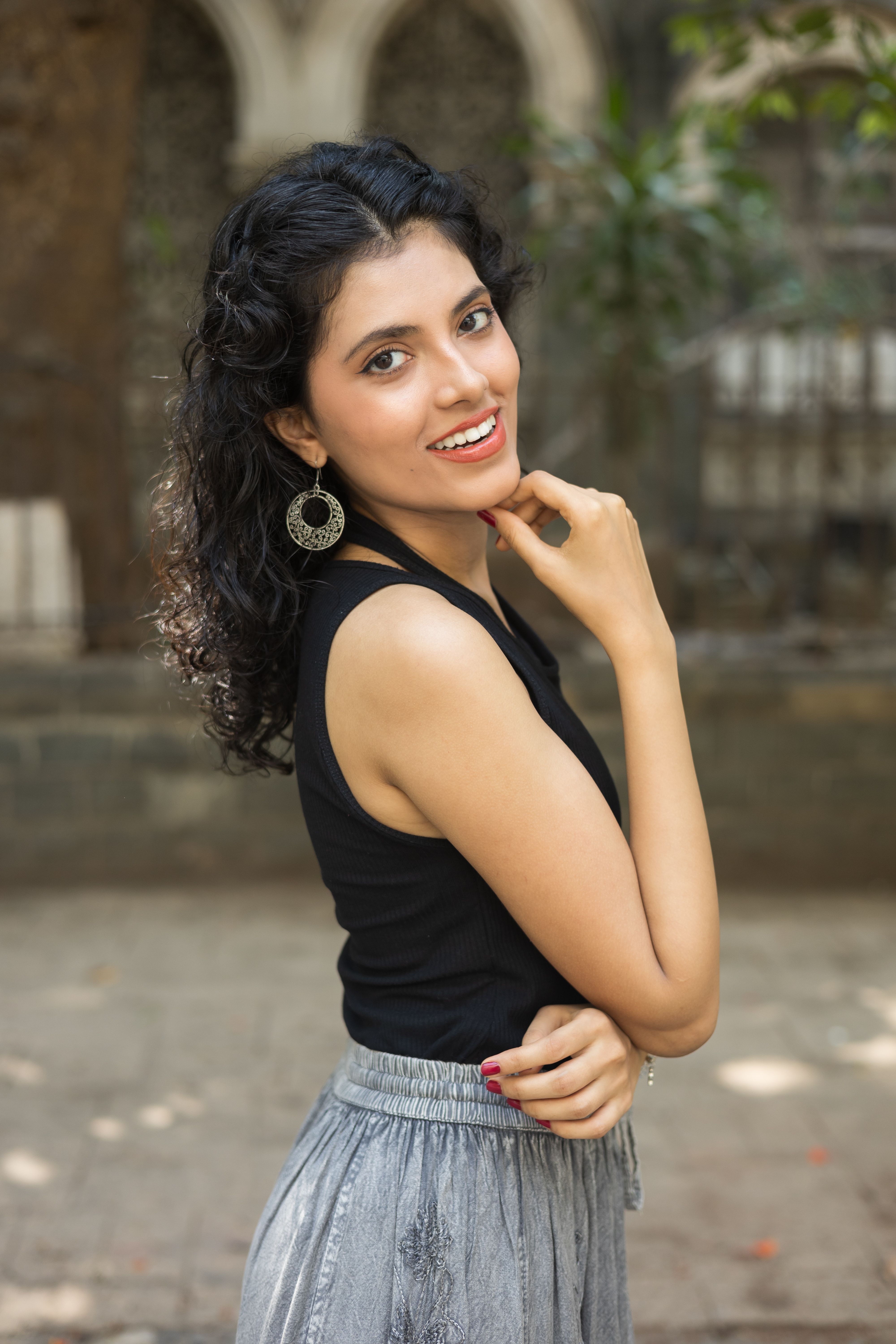 Portrait of a smiling woman in stylish clothing posing outdoors on a summer day.
