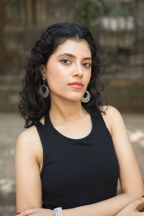 Free Portrait of a confident young woman outdoors wearing a black tank top and elegant earrings. Stock Photo