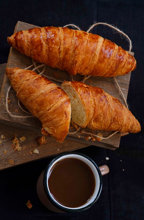 Free Two golden croissants with coffee on a wooden board. Perfect for breakfast or brunch imagery. Stock Photo