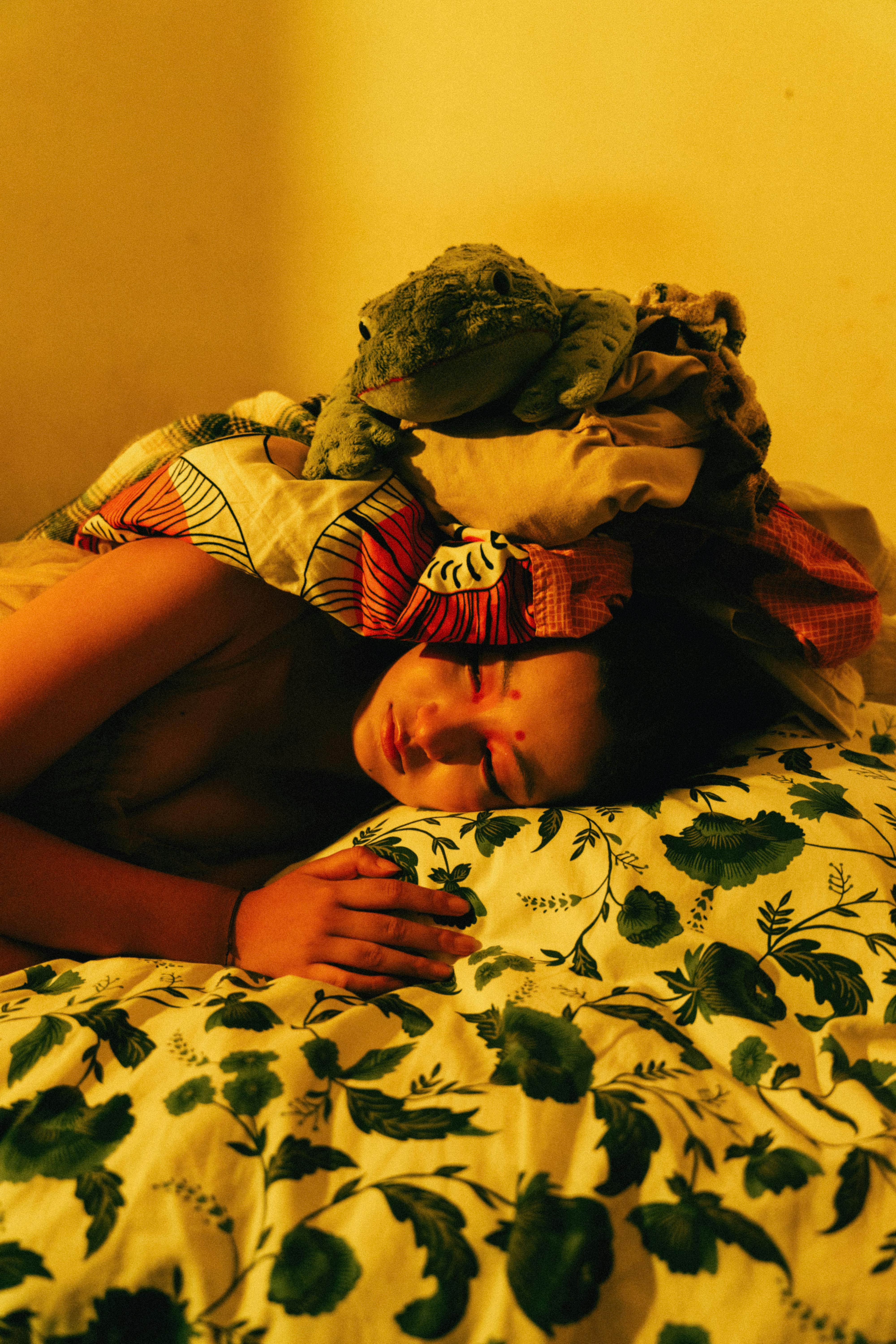 A woman sleeping peacefully under patterned fabric indoors, warm lighting.