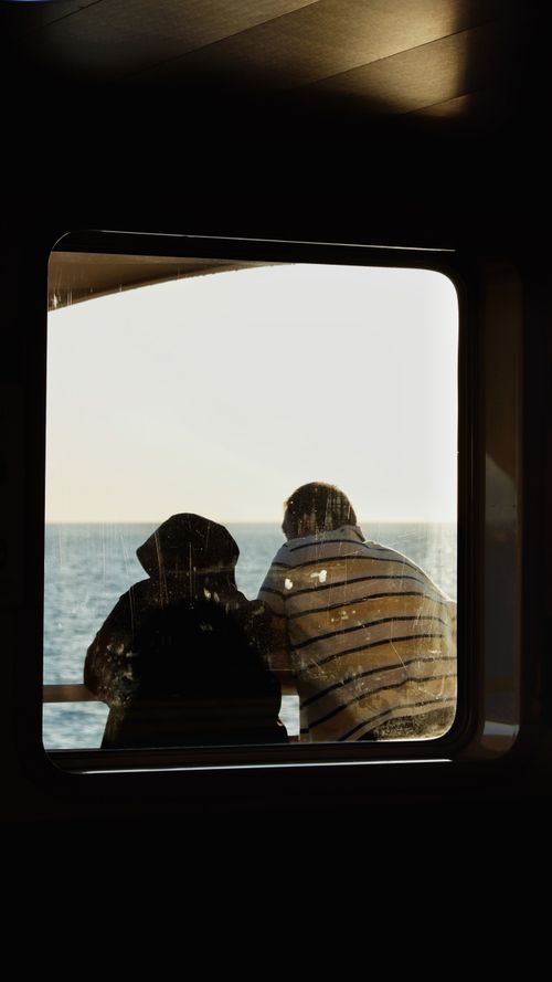 Free Silhouette of a couple enjoying a serene ocean view aboard a boat at sunset. Stock Photo