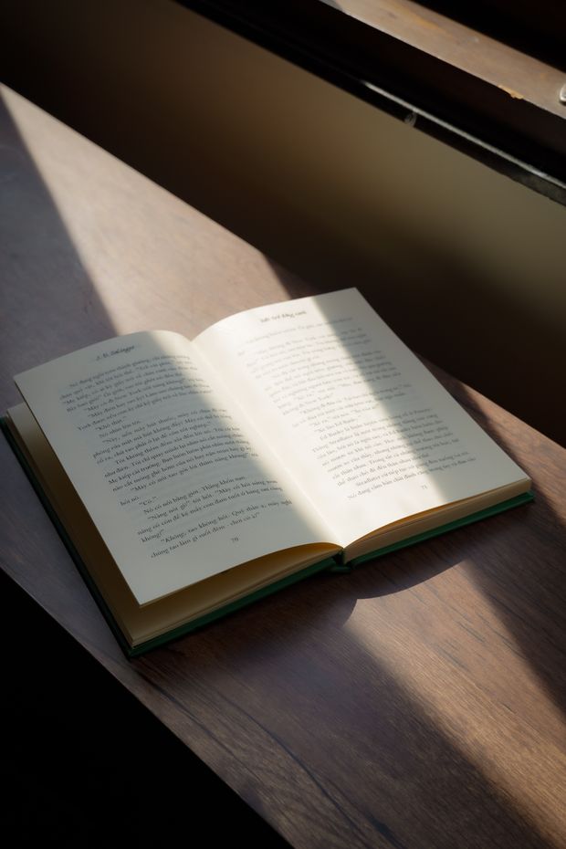 An open book resting in sunlight on a wooden table
