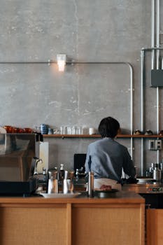 Barista preparing coffee in a stylish Yokosuka café with industrial design elements.