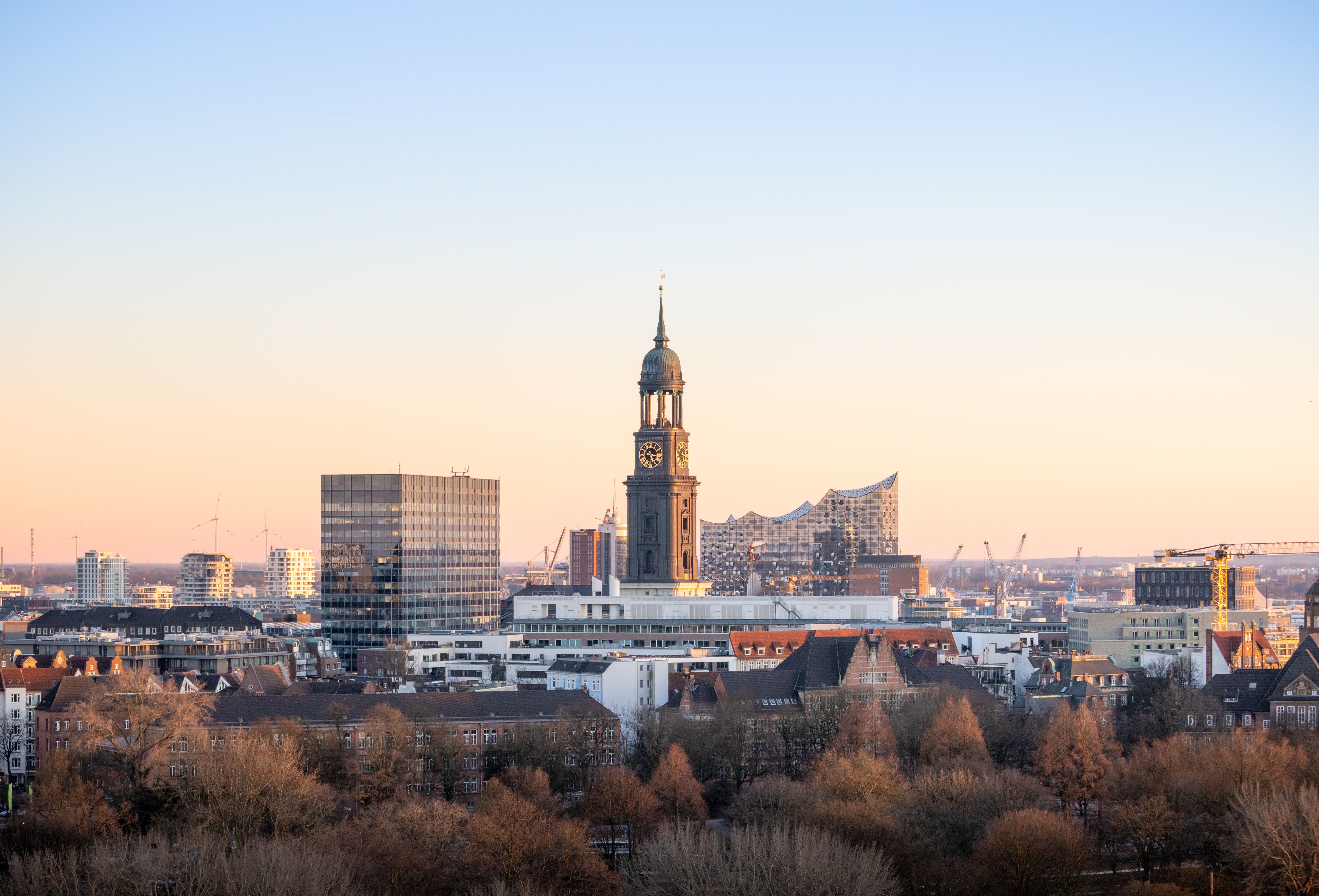 A picturesque view of Hamburg with St. Michael's Church and Elbphilharmonie at sunset.
